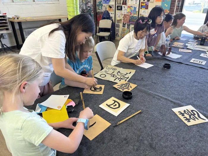 Children trying calligraphy on the floor of the hall