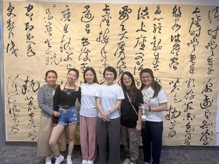 A group photo against the calligraphy wall