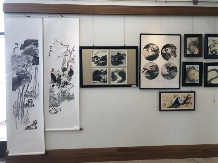 Scrolls and framed work along the wall